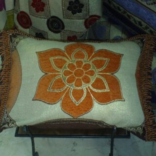 Housse de coussin marocaine jaune orangé ornée de motifs en fleur et cernée d'un liseré.